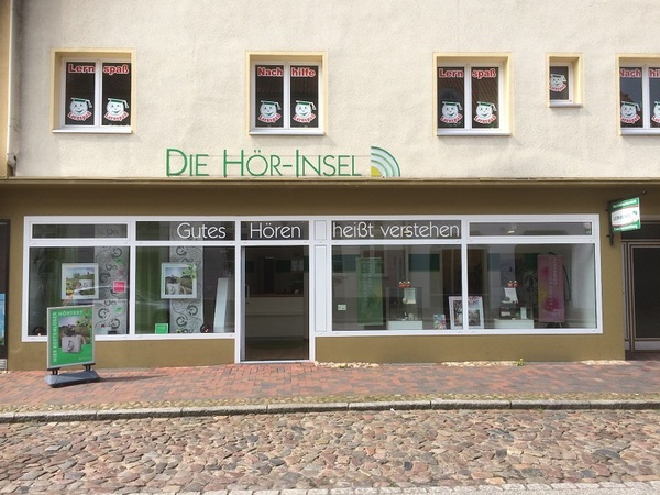 Fassade eines Hörakustik-Fachgeschäfts mit großem Schaufenster und Werbeschildern.